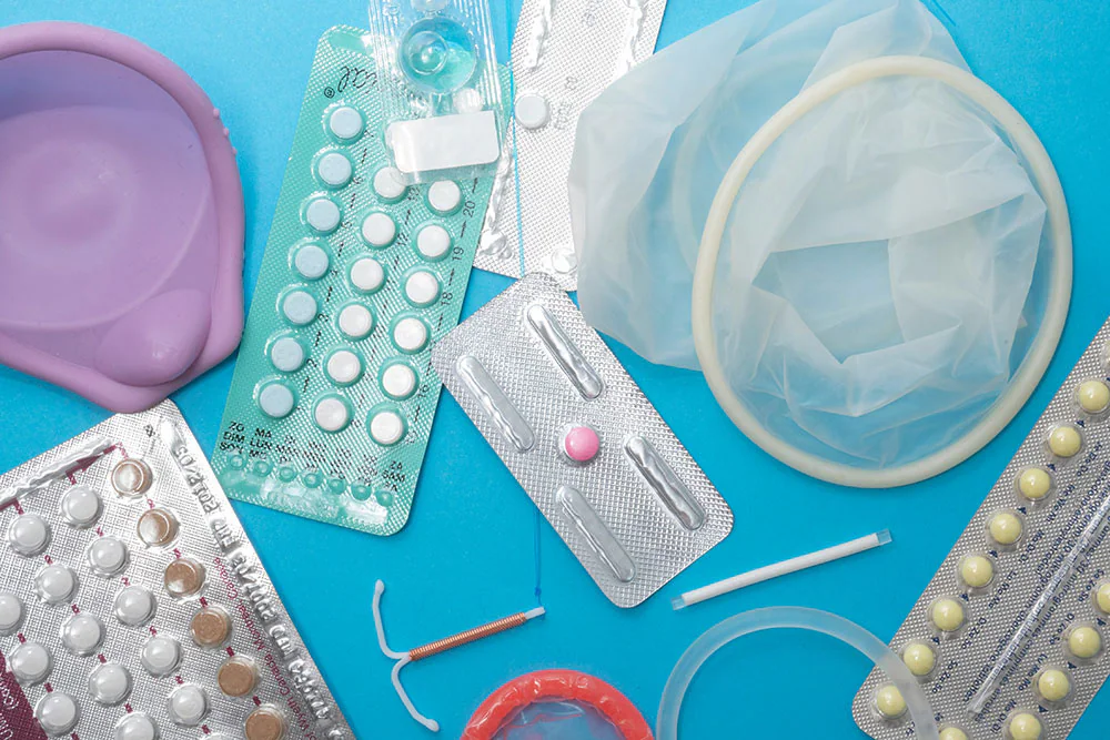 Assorted blister packs of contraceptive pills in blue, brown, and white tablets