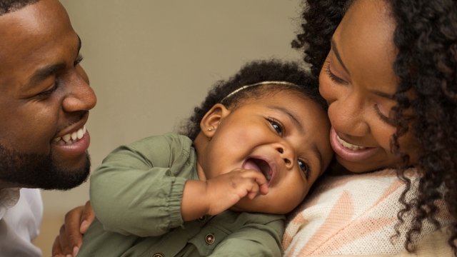 Smiling parents hold their baby close, showing the positive impact of family planning voucher programs on women and families