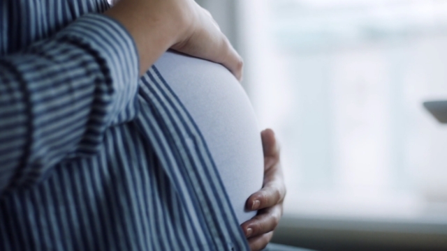 A pregnant woman holds her belly, showing the need for better global policies on maternal mortality