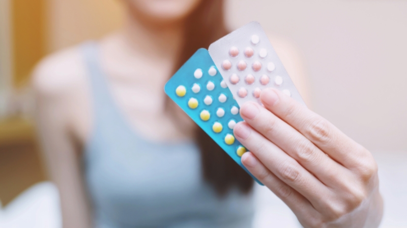 A woman holds two packs of birth control pills
