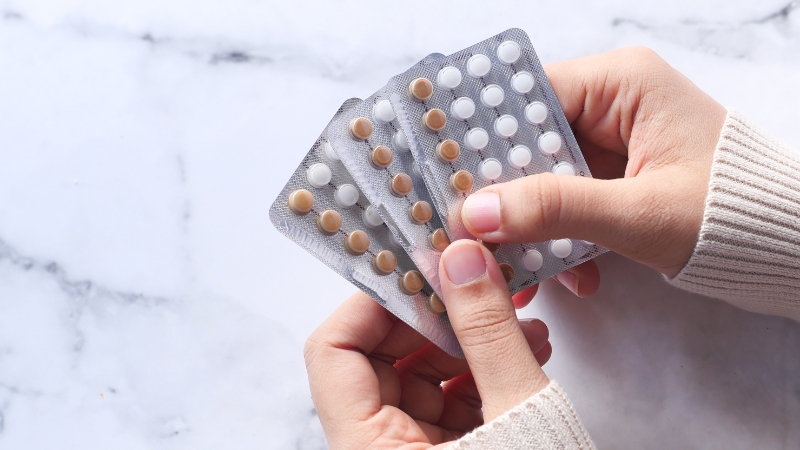 Hands holding several packs of birth control pills
